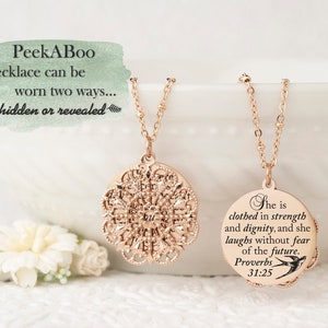May include: A rose gold PeekABoo necklace with a filigree pendant and a round pendant with the text "She is clothed in strength and dignity, and she laughs without fear of the future. Proverbs 31:25". The necklace can be worn two ways: hidden or revealed.