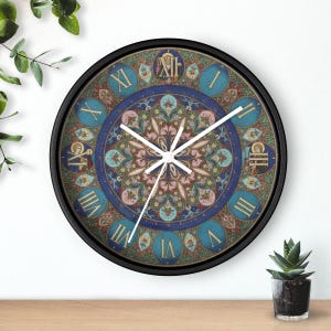 May include: A round wall clock with a black frame and white hands. The clock face features a central intricate floral mandala pattern in shades of blue, pink, and green, surrounded by a ring of Roman numerals on blue circular backgrounds.