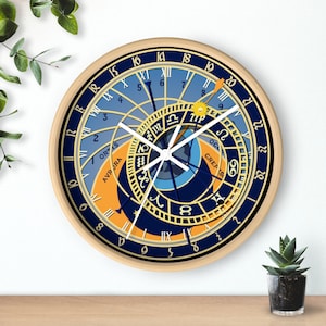 May include: A round, wooden-framed clock with a blue and gold face. The clock face features Roman numerals, zodiac symbols, and a detailed design of the sun and moon. The clock hands are white.