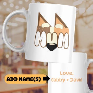 May include: White ceramic mug with a cartoon fox face and the word "MUM" in large, white letters. The mug has a black handle and the text "Love, Gabby + David" is printed on the bottom.