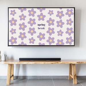 Puede incluir: Una pantalla de televisión muestra un patrón floral con flores moradas y centros amarillos sobre un fondo crema. Las palabras "spring break:" están en el centro. El televisor está encima de un banco de madera con una barra de sonido.