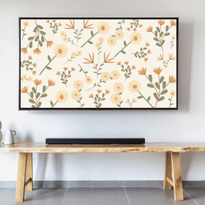 Puede incluir: Un televisor de pantalla plana con un estampado floral en la pantalla. El televisor está montado en una pared blanca sobre un estante de madera con una barra de sonido negra.