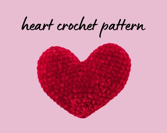 May include: A plush, red crocheted heart against a light pink background. The words "heart crochet pattern" are written in black script above the heart. The heart is a soft, textured craft item.