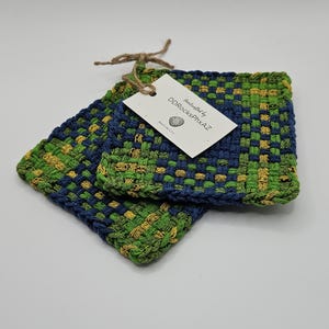 May include: Two square woven coasters in green, blue, and yellow. The coasters are made of a thick, textured material and have a woven pattern. A tag tied with twine reads "handcrafted by DDRocksPhxAZ."