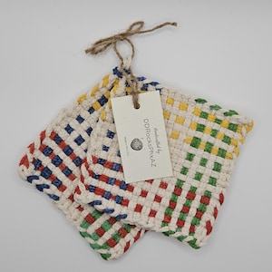 May include: Two woven square pot holders in red, blue, green, and yellow checkered patterns. The pot holders are made of a natural fiber and have a tag that reads "Handcrafted by DDRocksPhxAZ".