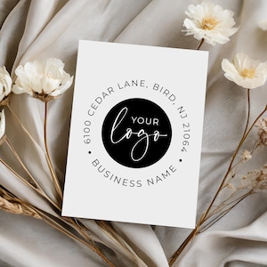 May include: A white card with a black circle stamp. The stamp says "6100 Cedar Lane, Bird, NJ 21064" and "Your Logo" in a circle with the text "Business Name" below.