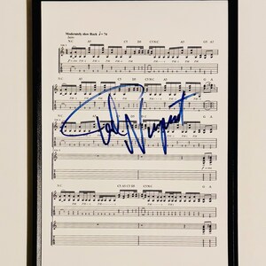 Pode incluir: Partitura emoldurada com notas musicais e uma assinatura azul. O texto "Moderately slow Rock J=74" é visível no topo. A moldura é preta.