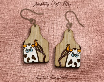 May include: Wooden earrings with a cow design. Each earring features a light brown tag shape with a cartoon cow face, a rope, and an orange bird. The text "Amazing Craft Files" and "digital download" are visible.