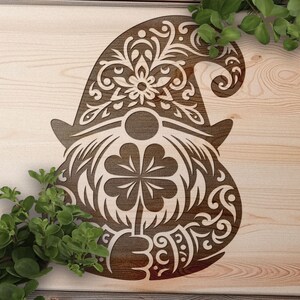 Può includere: Un tagliere di legno con un design decorativo di un gnomo che tiene un trifoglio a quattro foglie. Lo gnomo indossa un cappello con intricati motivi floreali.