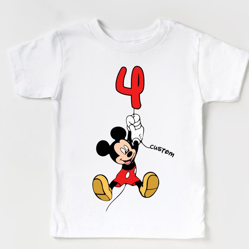 May include: White t-shirt featuring a cartoon Mickey Mouse holding a red number 4 balloon. Mickey is wearing red shorts, yellow shoes, and a red jacket. The word "custom" is written in black script.