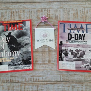 May include: Two vintage TIME magazine covers with red borders. One cover reads "Day of Infamy" with a photo of a ship in flames. The other cover reads "D-Day" with a photo of soldiers. A small banner reads "Frozen in Time Antiques."