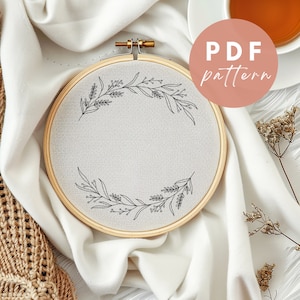 May include: A white embroidery hoop with a simple black floral design. The hoop is on a white fabric background with a brown circle that says "PDF pattern".