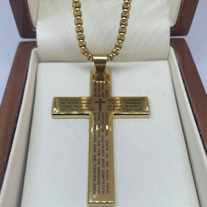 May include: Gold chain necklace with a gold cross pendant. The cross has the Lord's Prayer engraved on it.