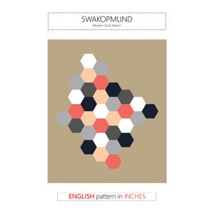 Peut inclure: Un modèle de courtepointe moderne appelé "Swakopmund" avec un motif géométrique d'hexagones en noir, blanc, gris, pêche et corail. Le motif est présenté sur un fond brun.