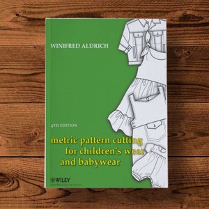 May include: A green book cover with the title "metric pattern cutting for children's wear and babywear" by Winifred Aldrich. The book is the 4th edition and is published by Wiley.