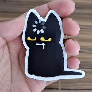 May include: A white ceramic mug with a black handle and the text "But First, Coffee" in a bold, black font. The mug is set against a neutral background, highlighting its simple design.