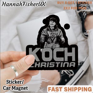 May include: A black and grey sticker or car magnet featuring an image of Christina Koch in a NASA spacesuit. The sticker has the name "KOCH CHRISTINA" in large, distressed lettering. The seller's name "HannahFisherUK" is at the top.