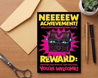 Peut inclure: Une carte de vœux rectangulaire sur fond noir illustrée d'un coffre au trésor marron entouré d'une explosion rose. Le texte indique : NEEEEEW ACHIEVEMENT! YOU SURVIVED ANOTHER YEAR. REWARD: ANOTHER YEAR WITH US. AND THIS CARD. YOU'RE WELCOME!