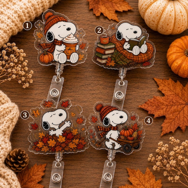 May include: Four acrylic badge reels featuring Snoopy in autumn-themed scenes. Design 1 shows Snoopy with a pumpkin drink, 2 shows Snoopy reading with books, 3 shows Snoopy in a pile of leaves, and 4 shows Snoopy with a pumpkin-filled wooden cart.