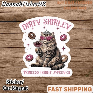 Op de afbeelding: Een sticker of auto-magneet met een cartoonkat met een zonnebril en een kroon, die een cocktail vasthoudt. De tekst luidt "Dirty Shirley" en "Princess Donut Approved". Donuts omringen de kat.
