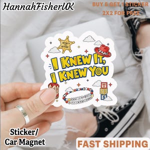 May include: A die-cut sticker featuring the yellow text I KNEW IT, I KNEW YOU, surrounded by illustrations of a gold sheriff badge, a red cowboy hat, a beaded bracelet with the text YOU'VE GOT A FRIEND IN ME, and three stacked alphabet blocks.