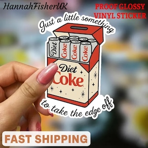 Puede incluir: Una pegatina de vinilo de Diet Coke con un diseño retro. La pegatina presenta una caja de seis latas de Diet Coke con el texto "Just a little something to take the edge off". La pegatina es roja, blanca y beige.