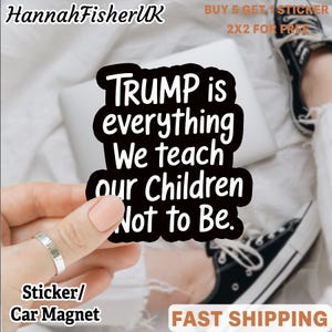 Puede incluir: Adhesivo en blanco y negro con el texto "TRUMP is everything We teach our Children Not to Be." El adhesivo está sujeto por una mano con un anillo plateado. También se ven las palabras "Sticker/ Car Magnet".