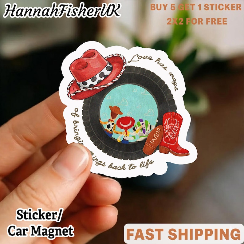 May include: A die-cut sticker featuring a black tire graphic framing a scene with cartoon characters. Above the tire is a red cowboy hat with a white and black spotted band. To the right is a red cowboy boot and a brown football labeled Taylor.
