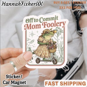 Peut inclure: Autocollant ou aimant de voiture avec une illustration d'une grenouille sur un scooter, portant une robe et un chapeau, et transportant un panier de fleurs. Le texte dit "Off to Commit Mom Foolery".
