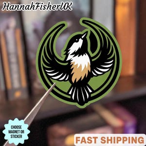 May include: A sticker or magnet featuring a stylized bird design. The bird is black and white with tan accents, set against a green background with a black outline. The text "HannahFisherUK" is at the top.