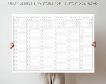 May include: A large white 2026 year planner with a grid layout, held by a person. The planner displays the months January through June. Text at the top reads "2026 YEAR PLANNER" and "MULTIPLE SIZES | PRINTABLE PDF | INSTANT DOWNLOAD."