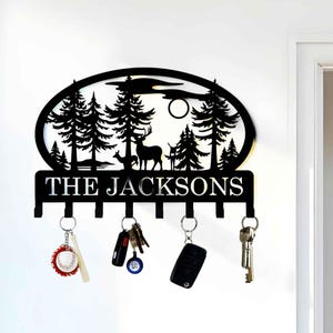 May include: Black metal key holder with a silhouette of a forest scene with deer and the text "THE JACKSONS".