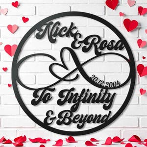 Puede incluir: Símbolo de infinito de metal negro con los nombres Nick & Rosa y la fecha 20.12.2004. El símbolo está rodeado por un círculo con el texto "To Infinity & Beyond".