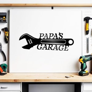 May include: Black metal wall art featuring a wrench with the text "Papa's Garage".