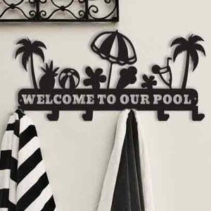 Peut inclure: Porte-manteau mural en métal noir avec le texte "WELCOME TO OUR POOL". Le porte-manteau présente des découpes décoratives de palmiers, d'un parasol de plage et d'autres formes sur le thème de l'été. Deux serviettes sont suspendues aux crochets.