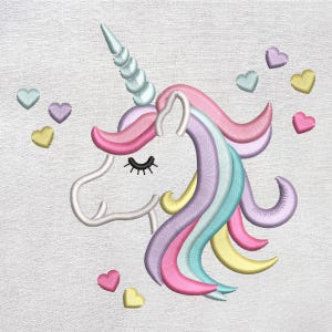 May include: Embroidered unicorn design with a spiraled horn, closed eye, and flowing mane in pink, purple, yellow, and blue. Pink, yellow, and teal hearts surround the unicorn on a white background. The design is likely for a child's item.