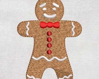 Peut inclure: Un bonhomme en pain d'épices brodé avec un visage souriant, un nœud papillon rouge et des boutons rouges. Le bonhomme en pain d'épices a des accents blancs et se trouve sur un fond blanc. Le design est probablement pour un artisanat ou une décoration sur le thème des fêtes.