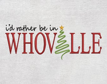 May include: White fabric with the embroidered phrase "i'd rather be in WHOVILLE". The text is in black and red, with a green Christmas tree and a yellow star. A festive holiday design.