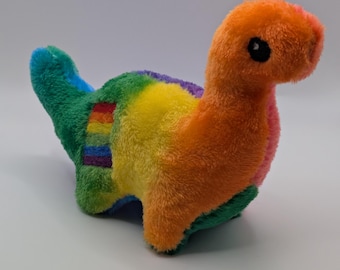 May include: A colourful plush dinosaur toy in shades of orange, yellow, green, and blue. The toy has a long neck and small head with black eyes. A rainbow stripe decorates the dinosaur's back.