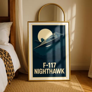 May include: Framed art print featuring an F-117 Nighthawk stealth fighter jet in flight against a dark blue night sky with a full moon. The text "F-117 NIGHTHAWK" is displayed in gold. The print is in a gold frame.