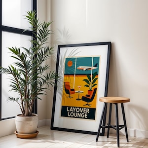 May include: A framed art print with a retro travel theme. The artwork features a stylized airplane, lounge chairs, and the text "LAYOVER LOUNGE" in a bold font. The color palette includes orange, yellow, and teal.