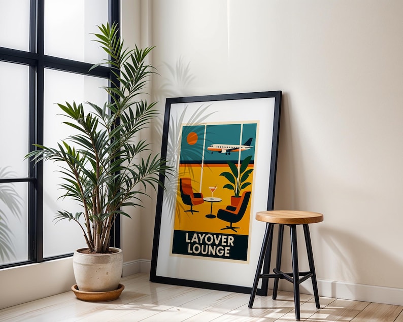 May include: A framed art print with a retro travel theme. The artwork features a stylized airplane, lounge chairs, and the text "LAYOVER LOUNGE" in a bold font. The color palette includes orange, yellow, and teal.