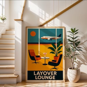 May include: A framed art print featuring a retro-style illustration of an airport lounge scene. The artwork depicts an airplane, a setting sun, two chairs, a table with a drink, and the text "LAYOVER LOUNGE" in a bold font. A potted plant is next to the artwork.