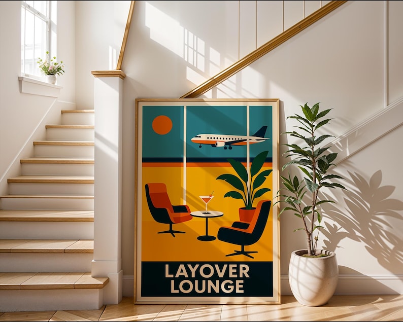 May include: A framed art print featuring a retro-style illustration of an airport lounge scene. The artwork depicts an airplane, a setting sun, two chairs, a table with a drink, and the text "LAYOVER LOUNGE" in a bold font. A potted plant is next to the artwork.