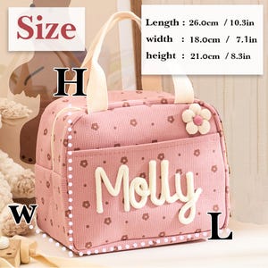May include: Pink lunch bag with a floral pattern and the name "Molly" in white. The bag has a white handle and a flower accent. Dimensions: 10.3 inches long, 7.1 inches wide, and 8.3 inches high.