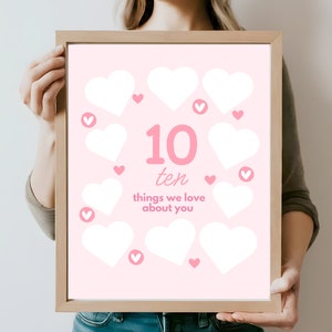 May include: A pink printable poster with a heart-shaped frame. The poster says "10 ten things we love about you" with 10 blank white hearts inside the frame.
