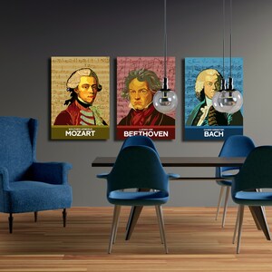 May include: Three framed posters of famous composers, Mozart, Beethoven, and Bach, hanging on a gray wall above a dark wood dining table with blue chairs.