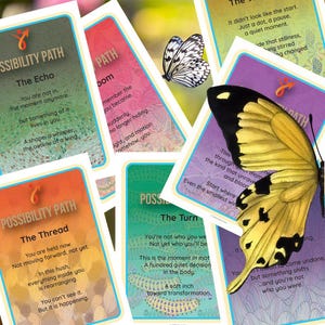 May include: A collection of colorful oracle cards with butterfly illustrations and inspirational text. The cards feature various color schemes, including green, orange, and purple, with white borders and the words "Possibility Path".