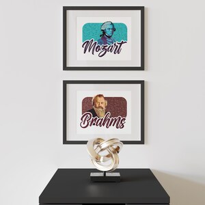 K&ouml;nnte beinhalten: Zwei gerahmte Drucke ber&uuml;hmter Komponisten, Mozart und Brahms, mit ihren Portr&auml;ts und Namen im Retro-Stil. Die Drucke werden an einer wei&szlig;en Wand &uuml;ber einer schwarzen Kommode mit einer silbernen Metallskulptur ausgestellt.