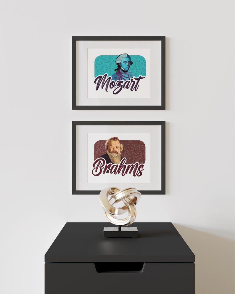 K&ouml;nnte beinhalten: Zwei gerahmte Drucke ber&uuml;hmter Komponisten, Mozart und Brahms, mit ihren Portr&auml;ts und Namen im Retro-Stil. Die Drucke werden an einer wei&szlig;en Wand &uuml;ber einer schwarzen Kommode mit einer silbernen Metallskulptur ausgestellt.